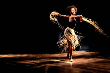 Çağdaş dansçı siyah arka plan ve saman aksesuarlarıyla tiyatroda dans ediyor. Salvador Bahia Brezilya.