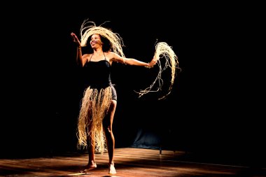 Çağdaş dansçı siyah arka plan ve saman aksesuarlarıyla tiyatroda dans ediyor. Salvador Bahia Brezilya.