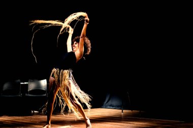 Çağdaş dansçı siyah arka plan ve saman aksesuarlarıyla tiyatroda dans ediyor. Salvador Bahia Brezilya.