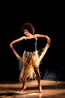 Çağdaş dansçı siyah arka plan ve saman aksesuarlarıyla tiyatroda dans ediyor. Salvador Bahia Brezilya.