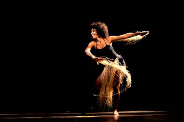 Çağdaş dansçı siyah arka plan ve saman aksesuarlarıyla tiyatroda dans ediyor. Salvador Bahia Brezilya.