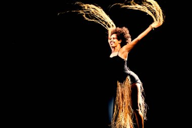 Çağdaş dansçı siyah arka plan ve saman aksesuarlarıyla tiyatroda dans ediyor. Salvador Bahia Brezilya.