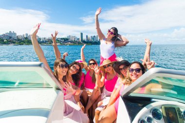 Arka planda denize karşı bir teknenin tepesindeki bayan arkadaşlar. Salvador, Bahia, Brezilya.