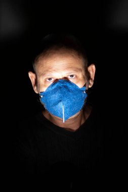 Siyah arka planda koruyucu maske takan bir adamın portresi. Salvador, Bahia, Brezilya