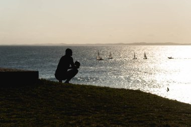 Oturmuş bir adamın silueti Salvador, Bahia, Brezilya 'da gün batımının keyfini çıkarıyor..