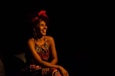 Tiyatroda bir sandalyede oturan aktris bir dizide bir karakteri canlandırıyor. Siyah arka plan. Salvador Bahia Brezilya.