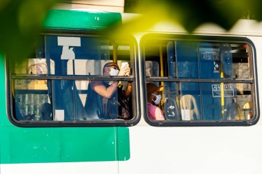 Salvador, Bahia, Brezilya - 30 Ekim 2020: Otobüsün içindeki insanlar koronavirüse karşı koruyucu maske takıyorlar. Salvador, Bahia, Brezilya.