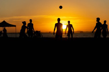 Salvador, Bahia, Brezilya - 23 Aralık 2020: Gençler gün batımında Brezilya 'nın Bahia kentindeki Ribeira plajında plaj futbolu oynuyorlar.