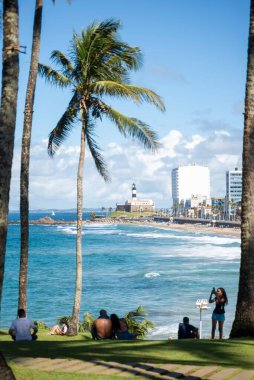Salvador, Bahia, Brezilya - 15 Ağustos 2021: Salvador, Bahia, Brezilya 'daki Farol da Barra plajının tadını çıkaran çok sayıda insanın arkası