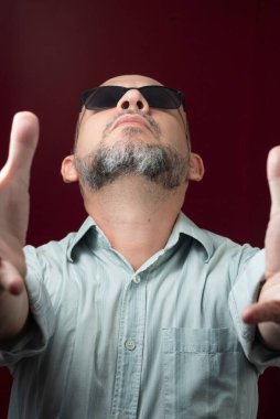 Kel ve sakallı bir adamın portresi. Kırmızı, koyu bir arka planda gözlük takıyor. Salvador, Bahia, Brezilya.