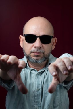 Kel ve sakallı bir adamın portresi. Kırmızı, koyu bir arka planda gözlük takıyor. Salvador, Bahia, Brezilya.