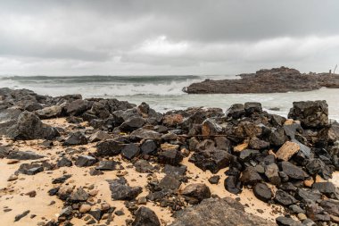 Dalgalı deniz sahildeki kayalara çarpıyor. Rio Vermelho, Salvador, Bahia, Brezilya.