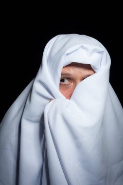 Siyah arka planda beyaz kumaşla kaplanmış bir adam. Salvador, Bahia, Brezilya.