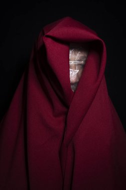 Yüzünde plastikle siyah arka planda kırmızı bez olan bir adam. Salvador, Bahia, Brezilya.