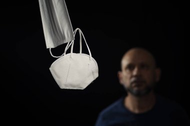 Siyah bir arka plan ve bir adama karşı iki koruyucu maskenin portresi. Salvador, Bahia, Brezilya.