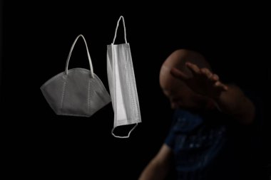 Siyah bir arka plan ve bir adama karşı iki koruyucu maskenin portresi. Salvador, Bahia, Brezilya.