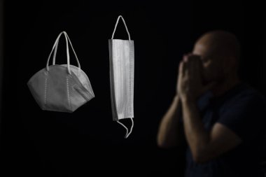 Siyah bir arka plan ve bir adama karşı iki koruyucu maskenin portresi. Salvador, Bahia, Brezilya.