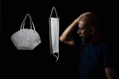 Siyah bir arka plan ve bir adama karşı iki koruyucu maskenin portresi. Salvador, Bahia, Brezilya.