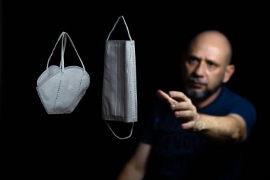 Siyah bir arka plan ve bir adama karşı iki koruyucu maskenin portresi. Salvador, Bahia, Brezilya.