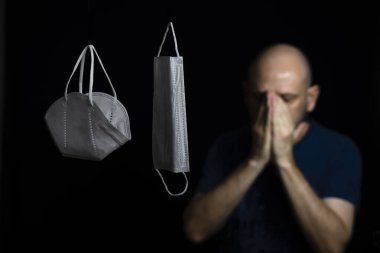 Siyah bir arka plan ve bir adama karşı iki koruyucu maskenin portresi. Salvador, Bahia, Brezilya.