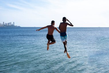 Salvador, Bahia, Brezilya - 31 Aralık 2021: Brezilya 'nın başkenti Bahia' daki Boa Viagem plaj iskelesinden atlayan genç atlayıcılar.