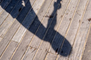 İskelenin ahşap zeminine yansıyan bir insanın gölgesi. Salvador, Bahia, Brezilya.