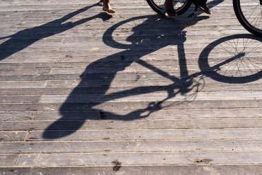 Bir rıhtımın ahşap zemininde bisikletli bir kişinin gölgesi. Salvador, Bahia, Brezilya.