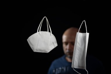 Siyah bir arka plan ve bir adama karşı iki koruyucu maskenin portresi. Salvador, Bahia, Brezilya.