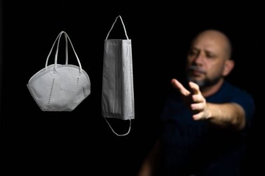 Siyah bir arka plan ve bir adama karşı iki koruyucu maskenin portresi. Salvador, Bahia, Brezilya.