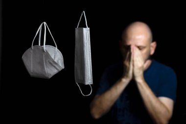 Siyah bir arka plan ve bir adama karşı iki koruyucu maskenin portresi. Salvador, Bahia, Brezilya.