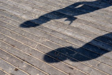 İskelenin ahşap zeminine yansıyan bir insanın gölgesi. Salvador, Bahia, Brezilya.
