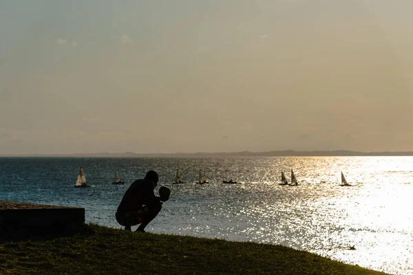 Salvador, Bahia, Brezilya - 01 Ekim 2021: Salvador, Bahia, Brezilya 'da günbatımının keyfini çıkaran oturan bir adamın silueti.