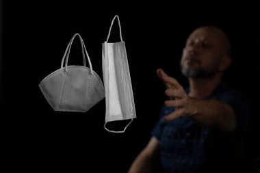 Siyah bir arka plan ve bir adama karşı iki koruyucu maskenin portresi. Salvador, Bahia, Brezilya.