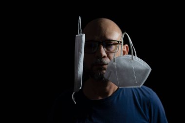 Covid-19 'a karşı iki koruyucu maskenin portresi ve siyah arka plana güvenen bir adam. Salvador, Bahia, Brezilya.