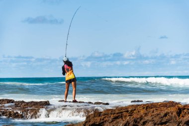 Salvador, Bahia, Brezilya - 10 Ekim 2021: Brezilya 'nın Bahia kentinin başkenti Salvador' da Rio Vermelho 'da kayalıklarda balık tutan balıkçı kadın