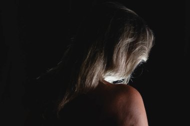 Sırtı kameraya dönük bir kadın stüdyoda siyah arka plana karşı. Salvador, Bahia, Brezilya.