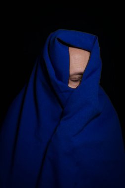 Siyah arka planda mavi kumaşla kaplanmış bir adam. Salvador, Bahia, Brezilya.