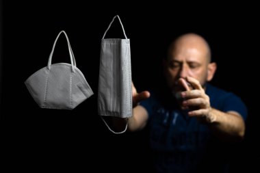 Siyah bir arka plan ve bir adama karşı iki koruyucu maskenin portresi. Salvador, Bahia, Brezilya.