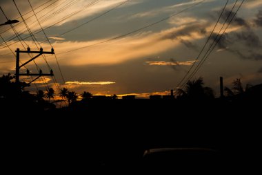 Dramatik günbatımına karşı binaların, direklerin ve kabloların silueti. Salvador, Bahia, Brezilya.