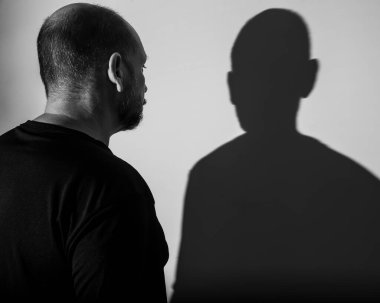 Beyaz duvar arkasında bir adamın ve gölgesinin portresi. Salvador, Bahia, Brezilya