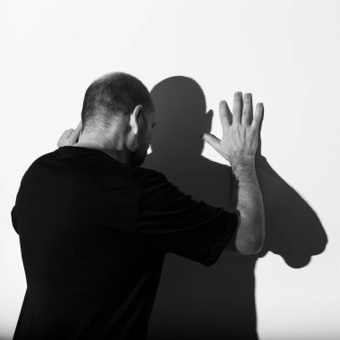 Beyaz duvar arkasında bir adamın ve gölgesinin portresi. Salvador, Bahia, Brezilya