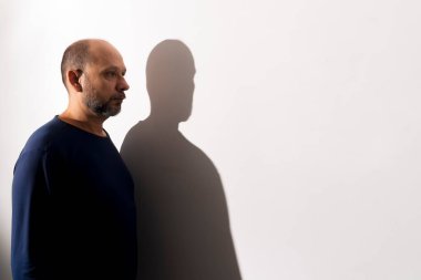 Beyaz duvar arkasında bir adamın ve gölgesinin portresi. Salvador, Bahia, Brezilya