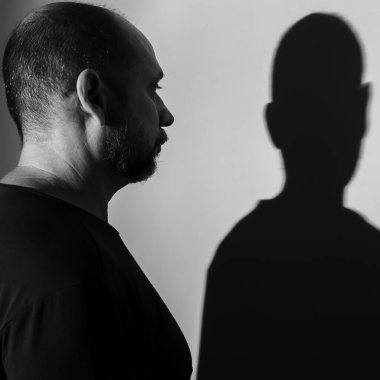 Beyaz duvar arkasında bir adamın ve gölgesinin portresi. Salvador, Bahia, Brezilya