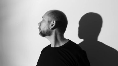 Beyaz duvar arkasında bir adamın ve gölgesinin portresi. Salvador, Bahia, Brezilya