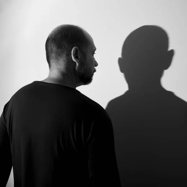 Portrait of a man and his shadow against white wall background. Salvador, Bahia, Brazil