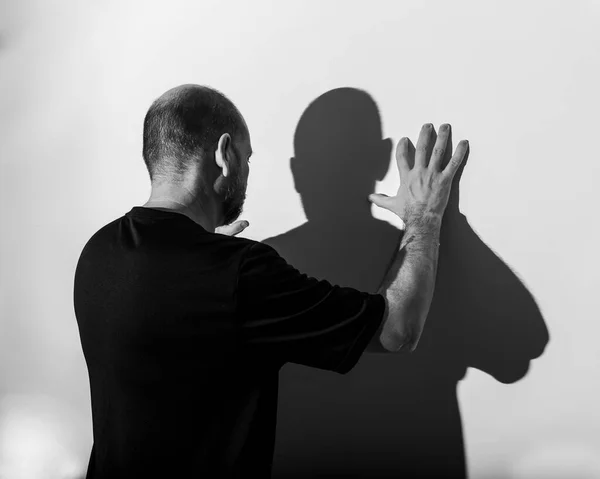 Portrait of a man and his shadow against white wall background. Salvador, Bahia, Brazil