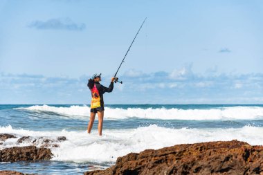 Salvador, Bahia, Brezilya - 10 Ekim 2021: Brezilya 'nın Bahia kentinin başkenti Salvador' da Rio Vermelho 'da kayalıklarda balık tutan balıkçı kadın