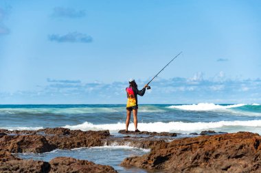Salvador, Bahia, Brezilya - 10 Ekim 2021: Brezilya 'nın Bahia kentinin başkenti Salvador' da Rio Vermelho 'da kayalıklarda balık tutan balıkçı kadın