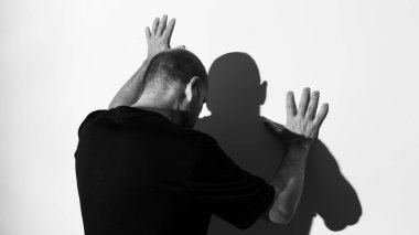 Beyaz duvar arkasında bir adamın ve gölgesinin portresi. Salvador, Bahia, Brezilya