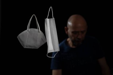 Siyah bir arka plan ve bir adama karşı iki koruyucu maskenin portresi. Salvador, Bahia, Brezilya.